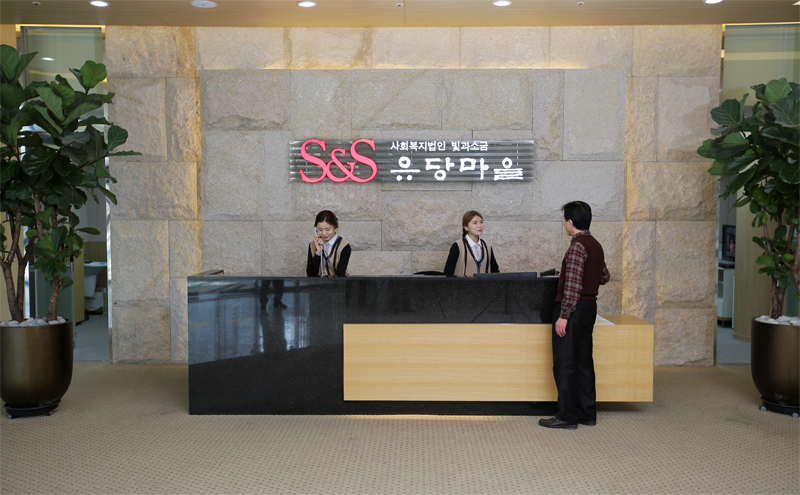 안내 직원과 방문객이 보이는 요양원 로비 안내데스크